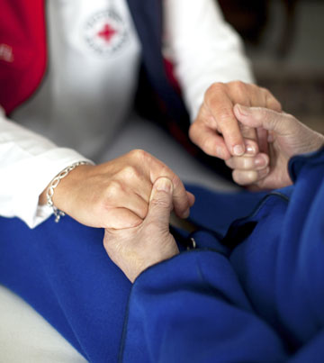 Foto: DRK-Helferin hält die Händer einer Seniorin (Ausschnitt der Hände)