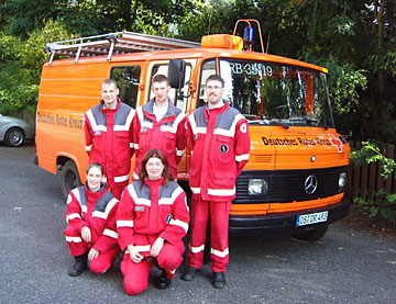 Foto: Gruppe von DRK-Helfern vor ihrem Einsatzfahrzeug.